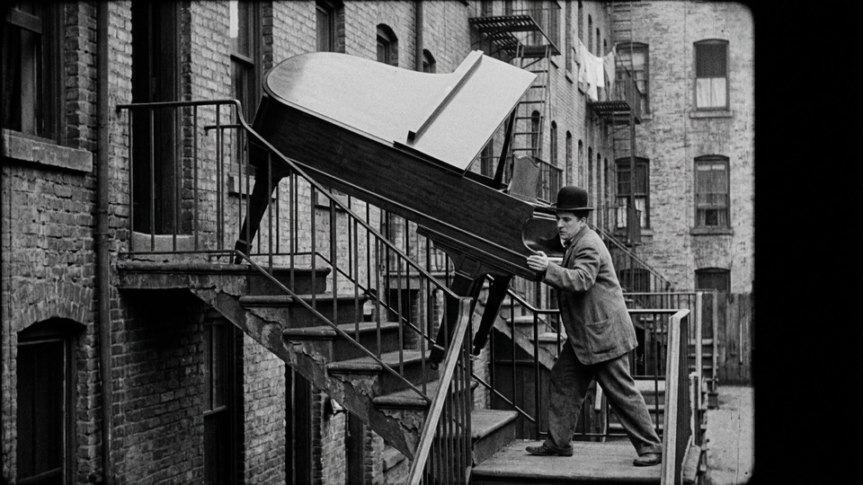 A lone [Chaplin-era everyman type] attempting [ambitious…